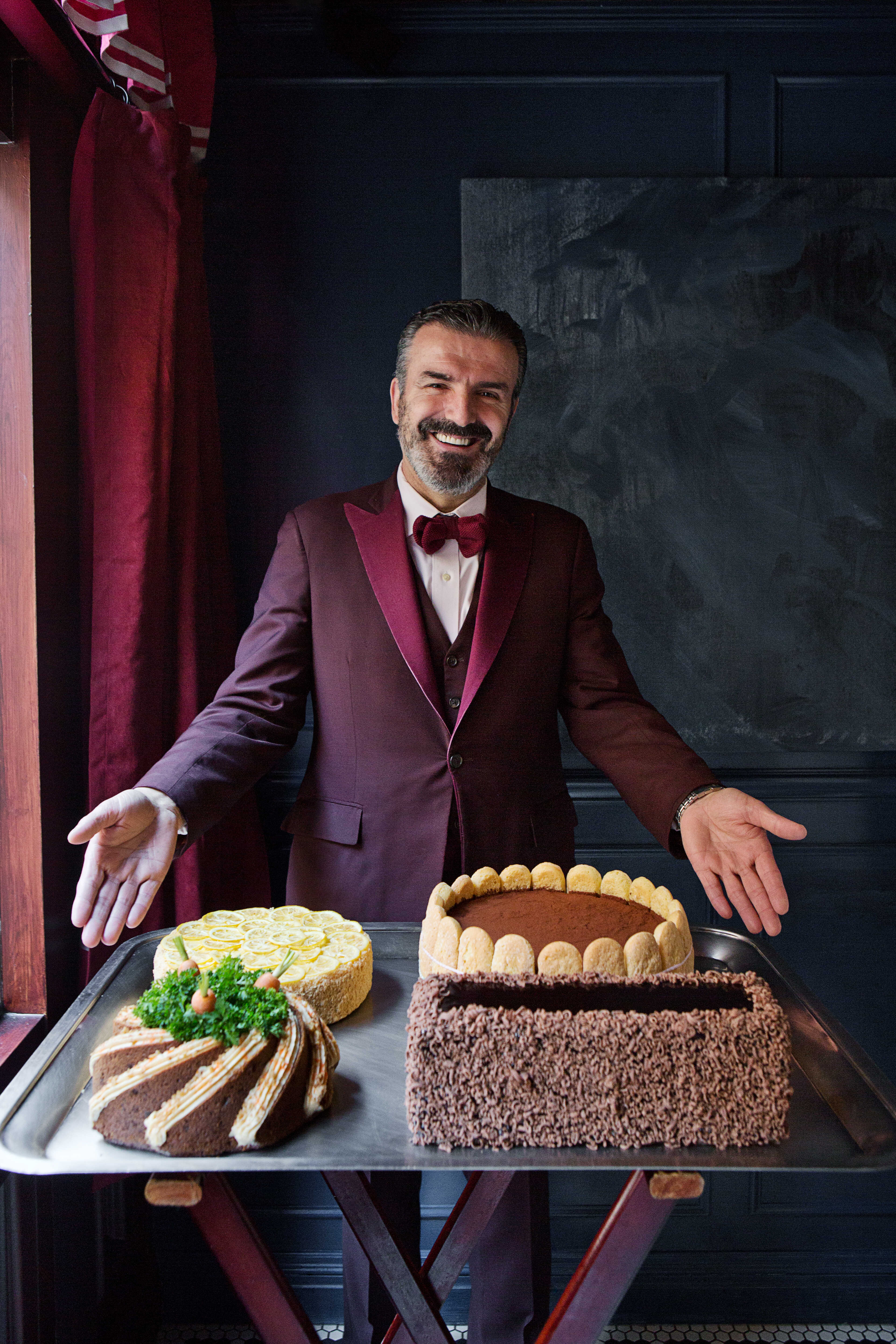 Waiter smiling while showcasing a large platter of desserts